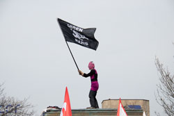 Antifaschistin schwenkt eine "Gegen Nazis"-Fahne auf dem Sockel auf dem Bahnhofsvorplatz